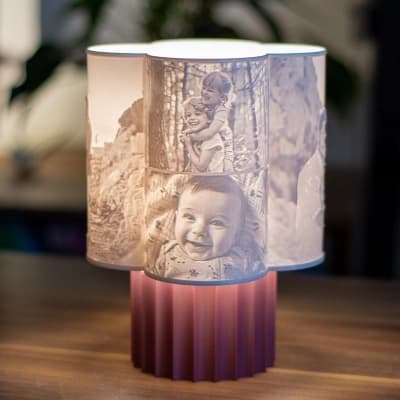 Flora personalisierte 3D-Fotolampe mit mehreren Familienporträts, die auf einem rosa Sockel in einem modernen Interieur leuchten.